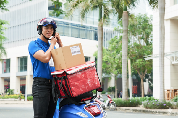 A delivery courier putting on his helmet to deliver a parcel, as part of final-mile delivery for last-mile fulfillment.