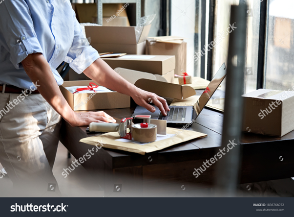 A warehouse staff lady leveraging omnichannel fulfillment for the online store and monitoring stock on a laptop