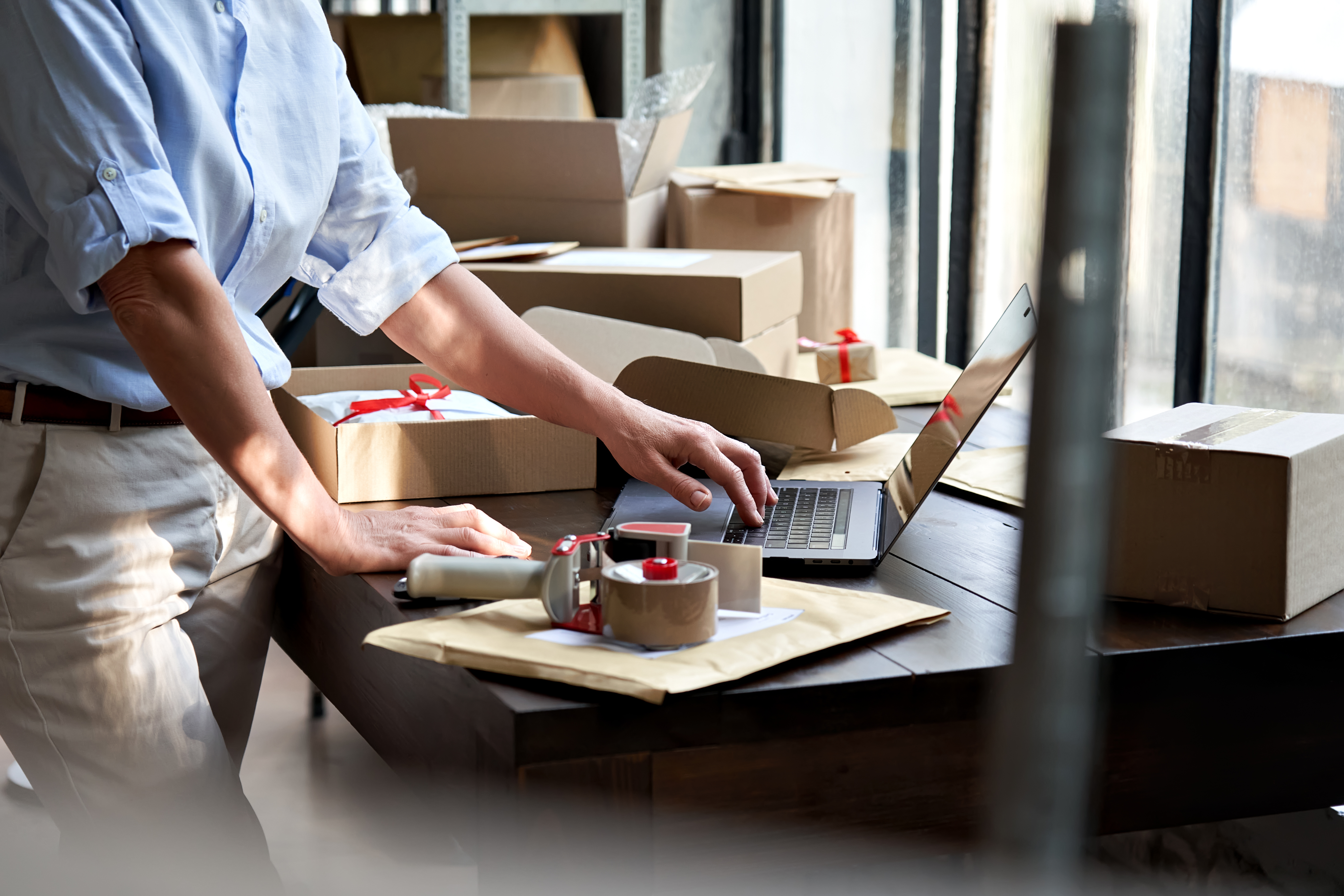 A warehouse staff lady leveraging omnichannel fulfillment for the online store and monitoring stock on a laptop